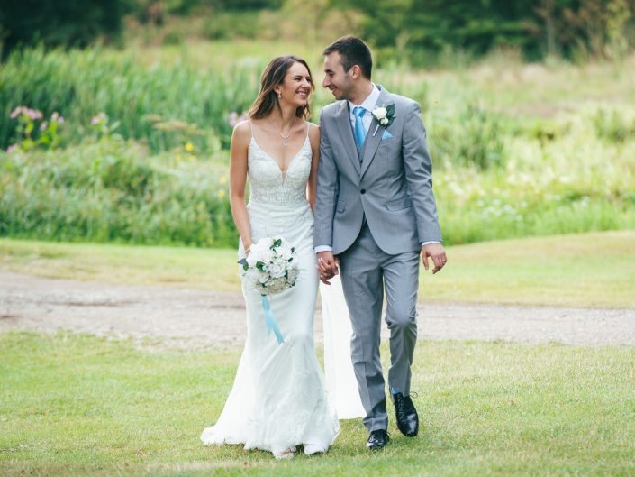 Wedding couple walking towards the camera on grass and looking at each other